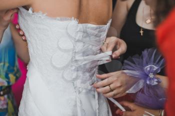 The girlfriend of the bride helps to dress a dress.