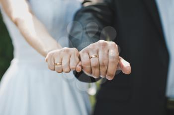Fists of the newly-married couple with wedding rings in them.