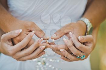 Mans palms embrace female with wedding rings.