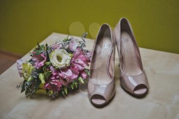 The bouquet and shoes lie on a table.