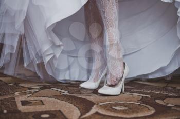 The girl in a wedding dress dresses shoes.