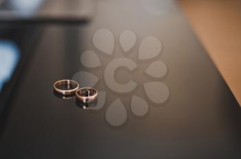 Wedding rings lie on a smooth table.