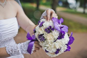 Bouquet from white and violet flowers in hands of the bride.