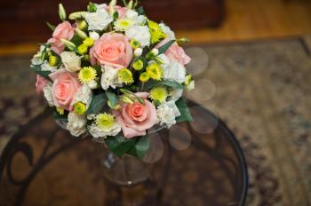 Bouquet from roses and other flowers on a glass table.