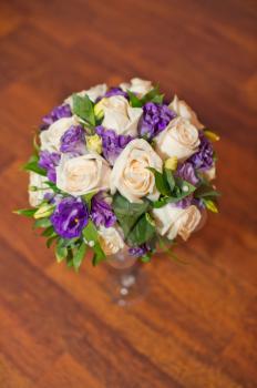 Bouquet from beige roses and violet flowers.