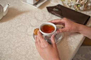 Hands holding a cup with tea.