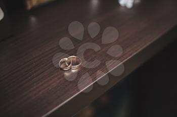 Wedding rings on a brown table.