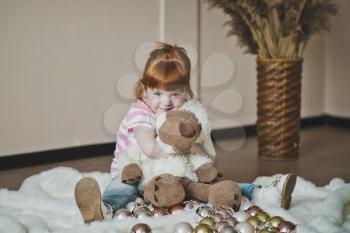 Fiery little girl playing with Christmas toys.