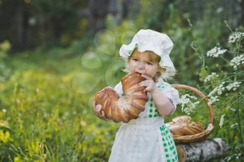 A child eats a fresh loaf in the garden.