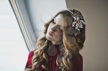 A girl with long brown hair by the window.