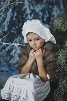 A girl in an old suit sitting in a winter tree.