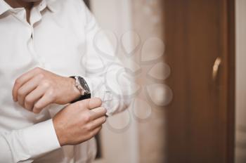 Hands of the young man clasping a shirt.