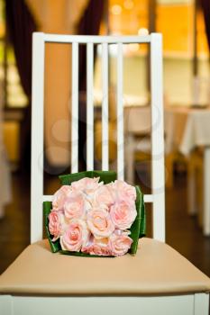 The bouquet from pink roses lies on a beige chair.