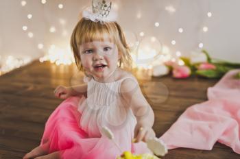 One year old girl in a festive dress and the crown.