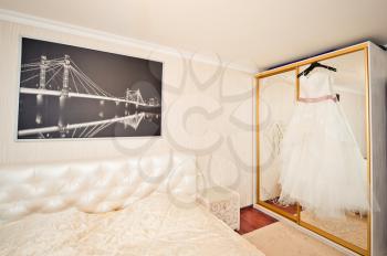 The wedding dress prepared for ceremony hangs in a beautiful room.