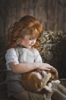 Child stroking a rabbit on her knees.
