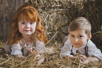 Boy and girl lie and play in the haystack.