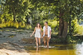 A young couple walking along the waters edge.
