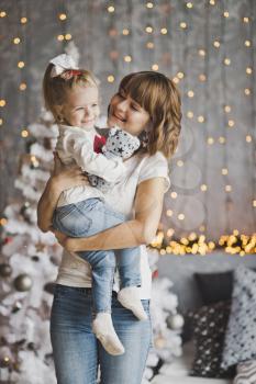 Joyful mother playing a daughter on the eve of the new year.