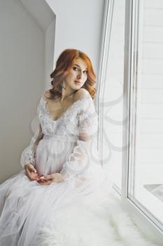 Close-up portrait of girl in a negligee on background of the window.