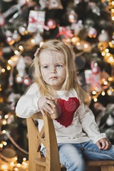 Portrait of a child on a background of Christmas tree decorated with balls.