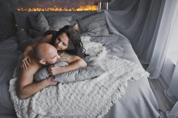Man and woman talking while lying on a soft bed.