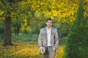 Portrait of the groom walking in the autumn garden.