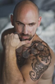 Brutal man with tattoo on shoulder and chest.