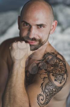 Portrait of a man with developed muscles and a tattoo.