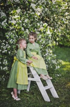 Children in a linen outfits playing in a cherry orchard.