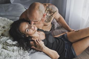 A girl and a young strong man kiss sitting on the windowsill.