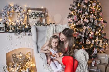 Portrait of a beautiful girl with her daughter on the background of sparkling Christmas garlands.