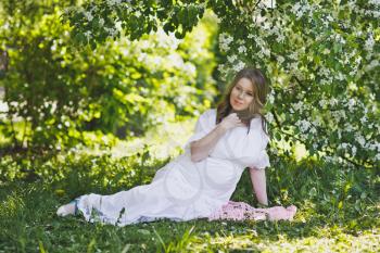 The girl reclines on the grass in the flower garden.