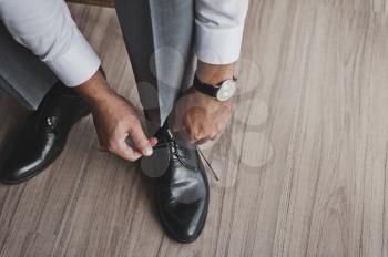 A man in a business suit ties his shoelaces.