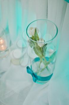 Decorative white roses are in a glass vase.