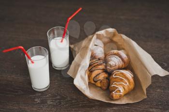 Bag with croissants and glasses of milk for Breakfast.