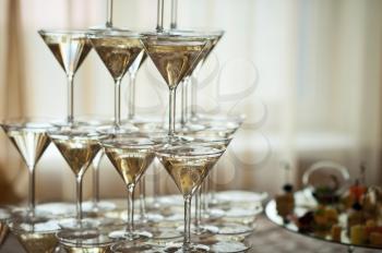 Pyramid of wine glasses with champagne on the background of the window.