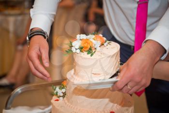 The process of cutting a delicious birthday cake decorated with flowers from edible materials.