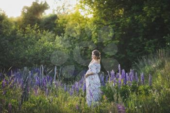 Beautiful portrait of a girl standing in the field of blooming Lupin.