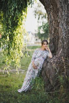 Portrait of a girl at the trunk of a weeping willow.