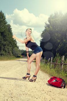 pin up girl standing on the road and catches sexy hitchhiking