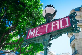 Traditional Paris metro sign with trees in the background