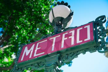 Traditional Paris metro sign with trees in the background