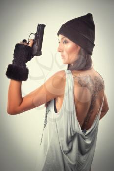 girl with tattoo with a gun standing in the studio
