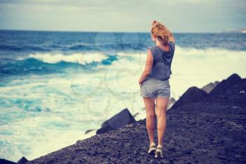 girl on the ocean watching the big waves
