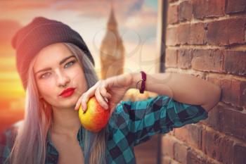 Girl with blue hair eating an apple on the background of Big Ben in London