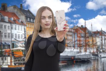 girl blogger shoots on a smartphone in the Nyhavn is the old harbor of Copenhagen. Denmark
