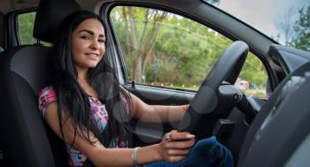 beautiful girl sits behind the wheel of a car