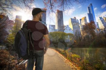 male traveler with a backpack is standing in the central park of New York