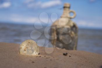 treasure from bitcoin on background of bottle with money on the beach